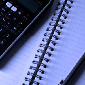 A calculator sitting on a notepad with a pencil