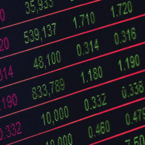 A digital screen displays stock market data with numbers in green and red, showing various prices and values in rows and columns on a black background.