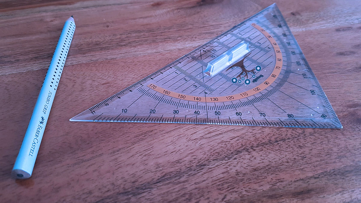 A protractor and pencil on a wood surface.