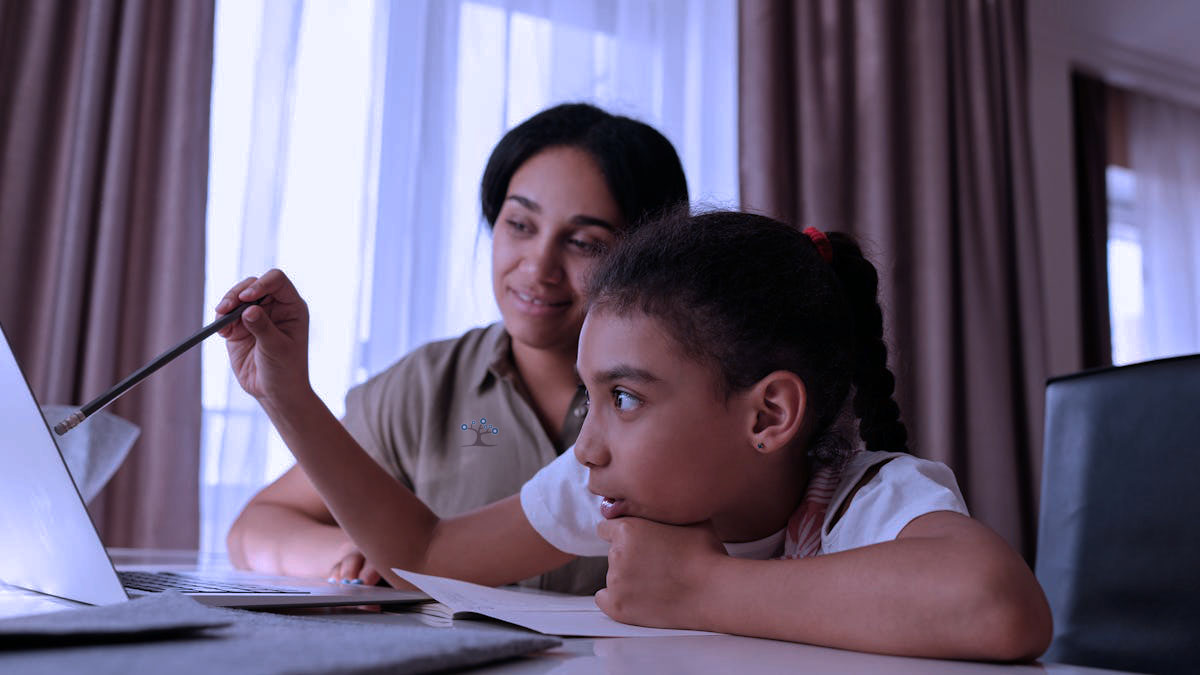 A young girl pointing at her laptop screen with a pencil in her hand while her mom looks over her shoulder with a smile.