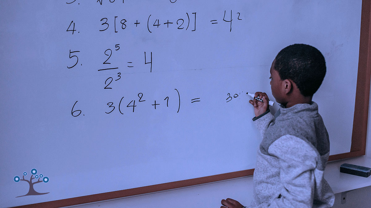 A boy writing math problems on a whiteboard with a marker.