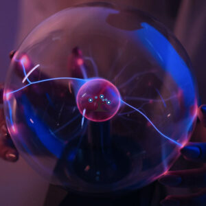 Hands holding a glass sphere with static charges inside.