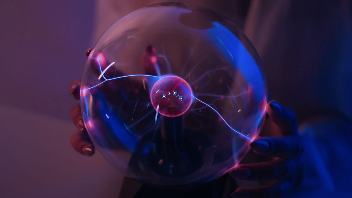 Hands holding a glass sphere with static charges inside.