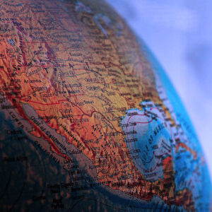 Close-up of a globe showing the southwestern United States and northern Mexico, including California, Texas, and the Gulf of Mexico, with soft blue and purple background lighting.