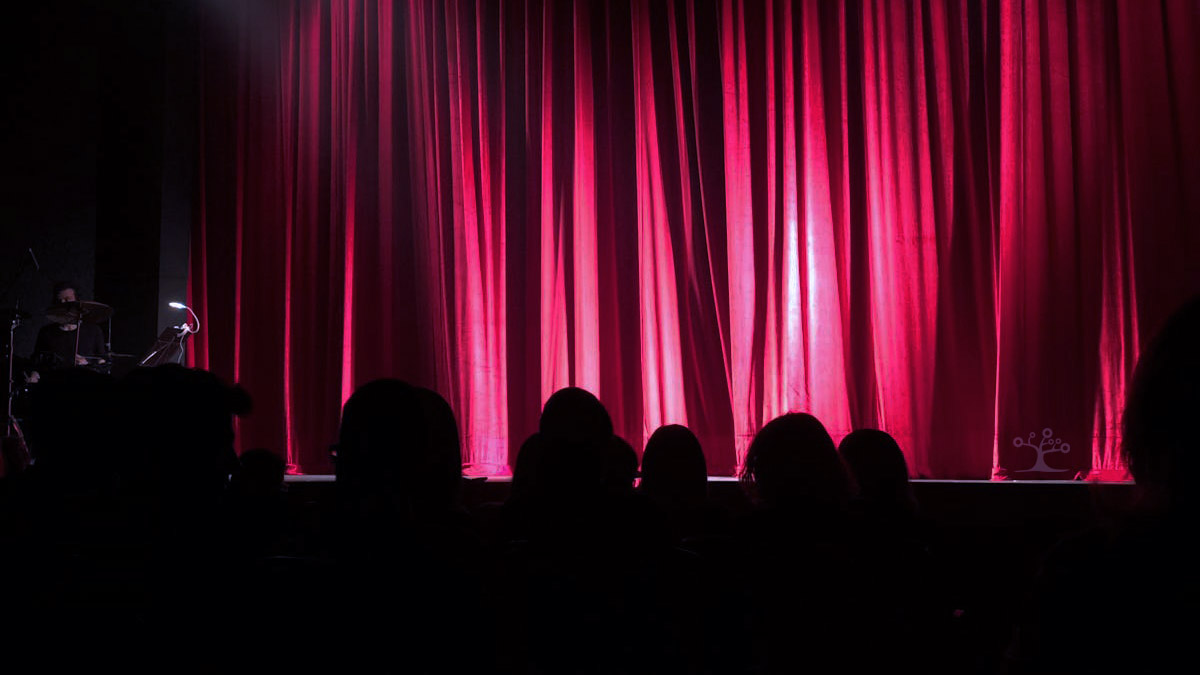 Stage with a spotlight on a red curtain.