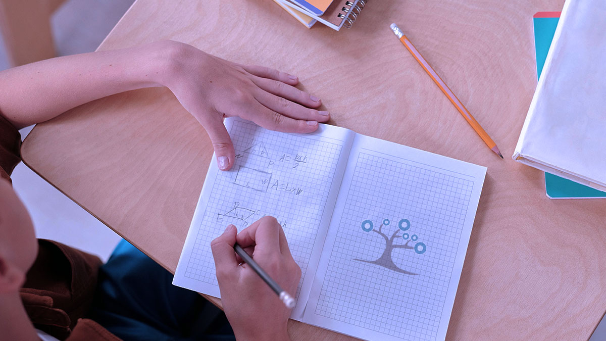 Student writing math problems in a workbook with a pencil